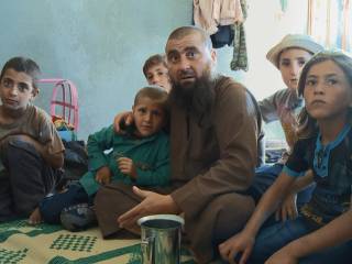 muž a skupina dětí sedí na dece na zemi v místnosti