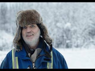 muž v teplé čepici na pozadí zasněžené krajiny