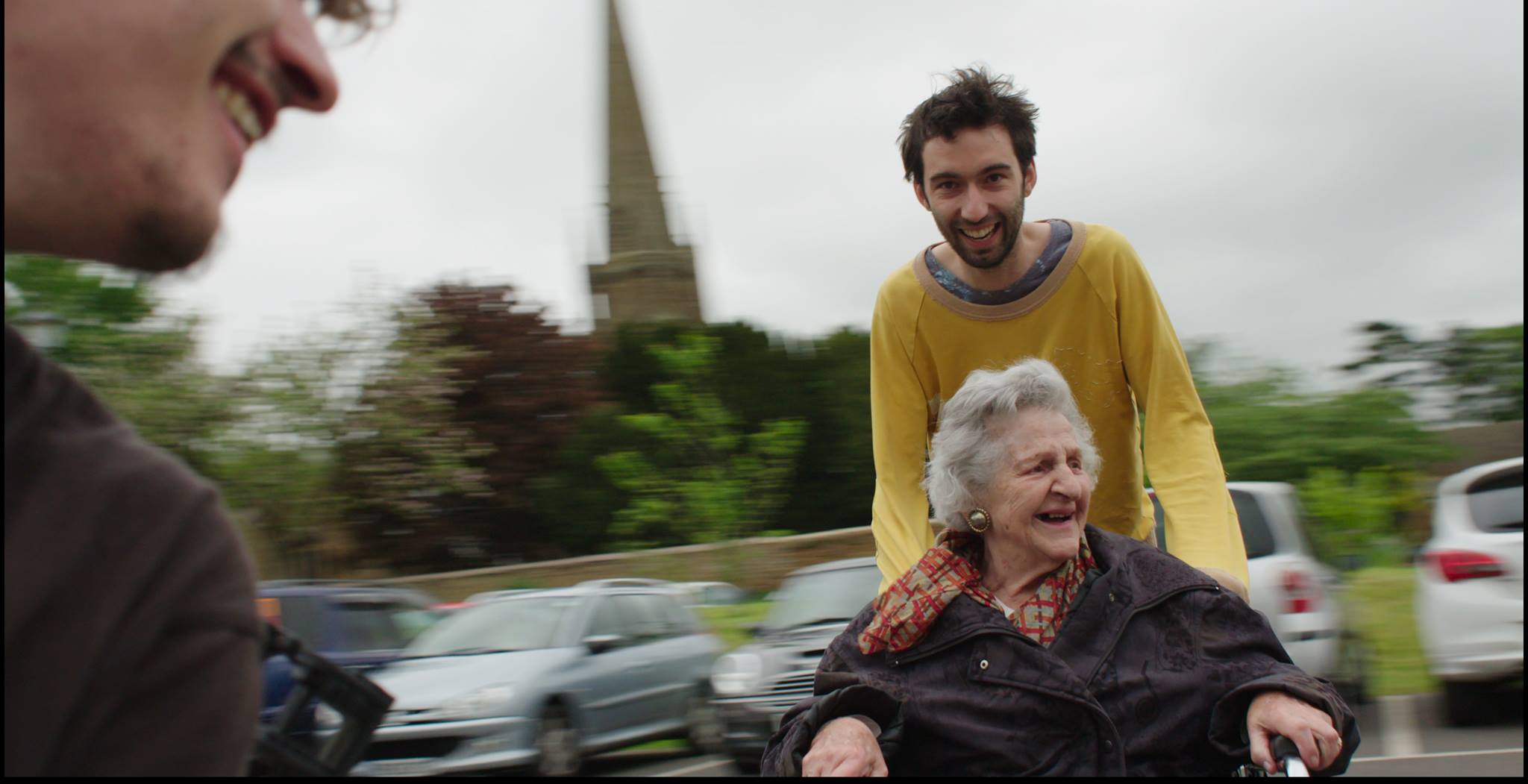 muž veze starou ženu na vozíku, oba se smějí